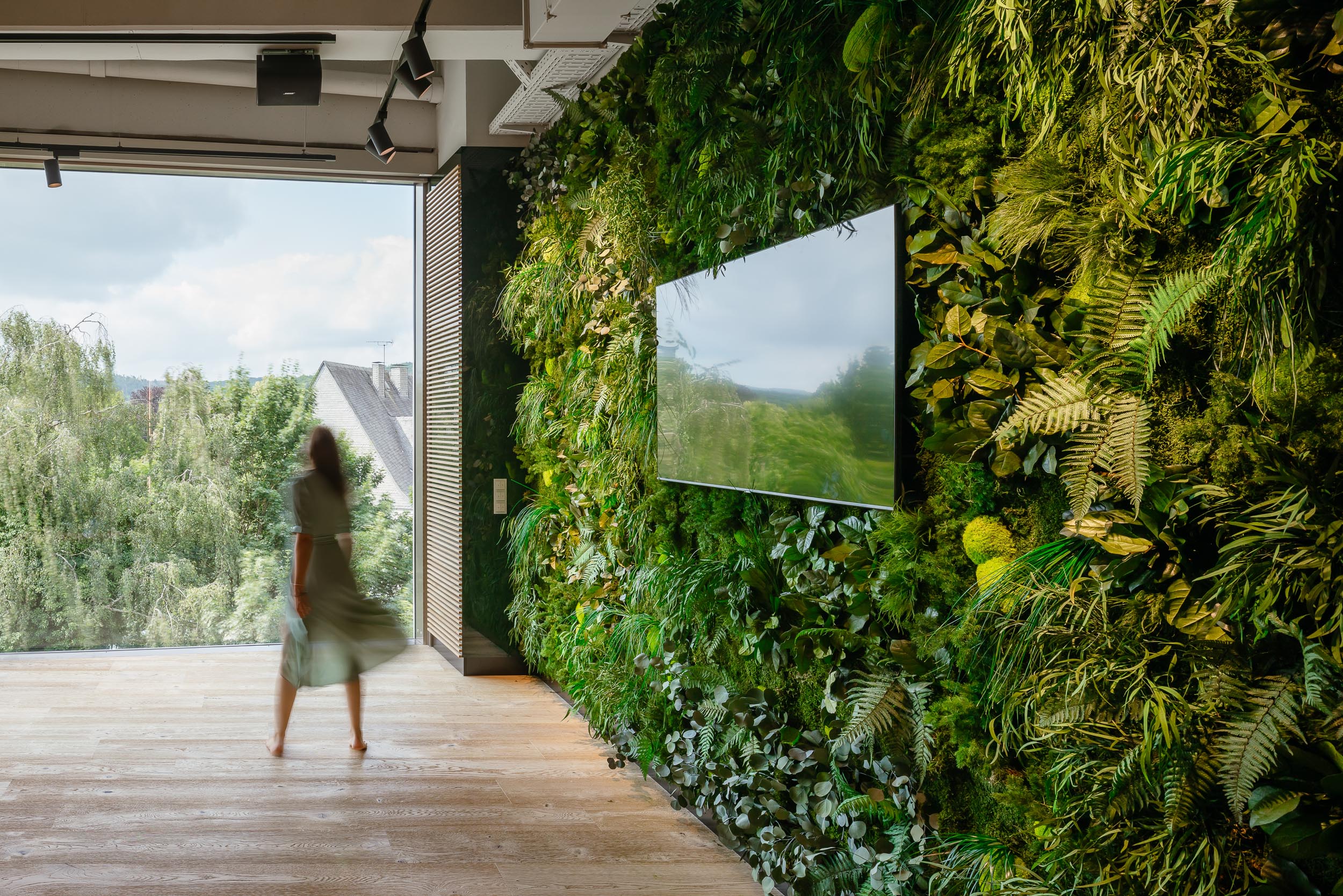 Large wall covering made of jungle moss with an integrated TV screen in a designer fashion shop